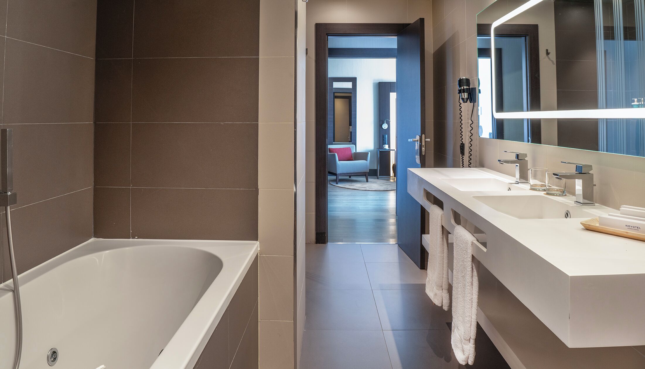 Ein modernes Badezimmer mit einer Badewanne, einem großen Spiegel und einem Waschtisch.