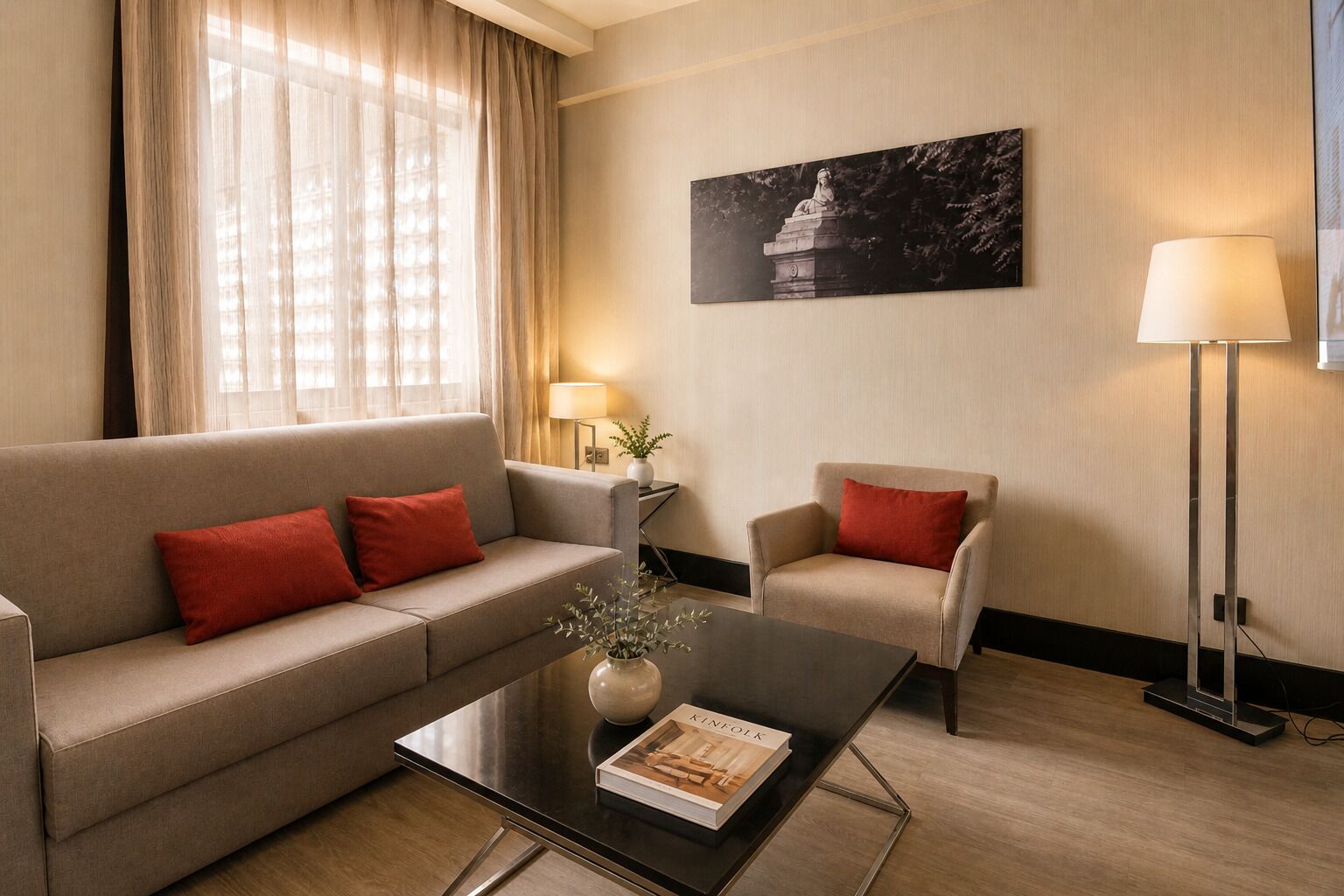 Habitación de hotel con sofá, sillón, mesa de centro y un cuadro en la pared.