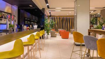 Zona de bar con taburetes, una barra y un área de asientos con sillas.