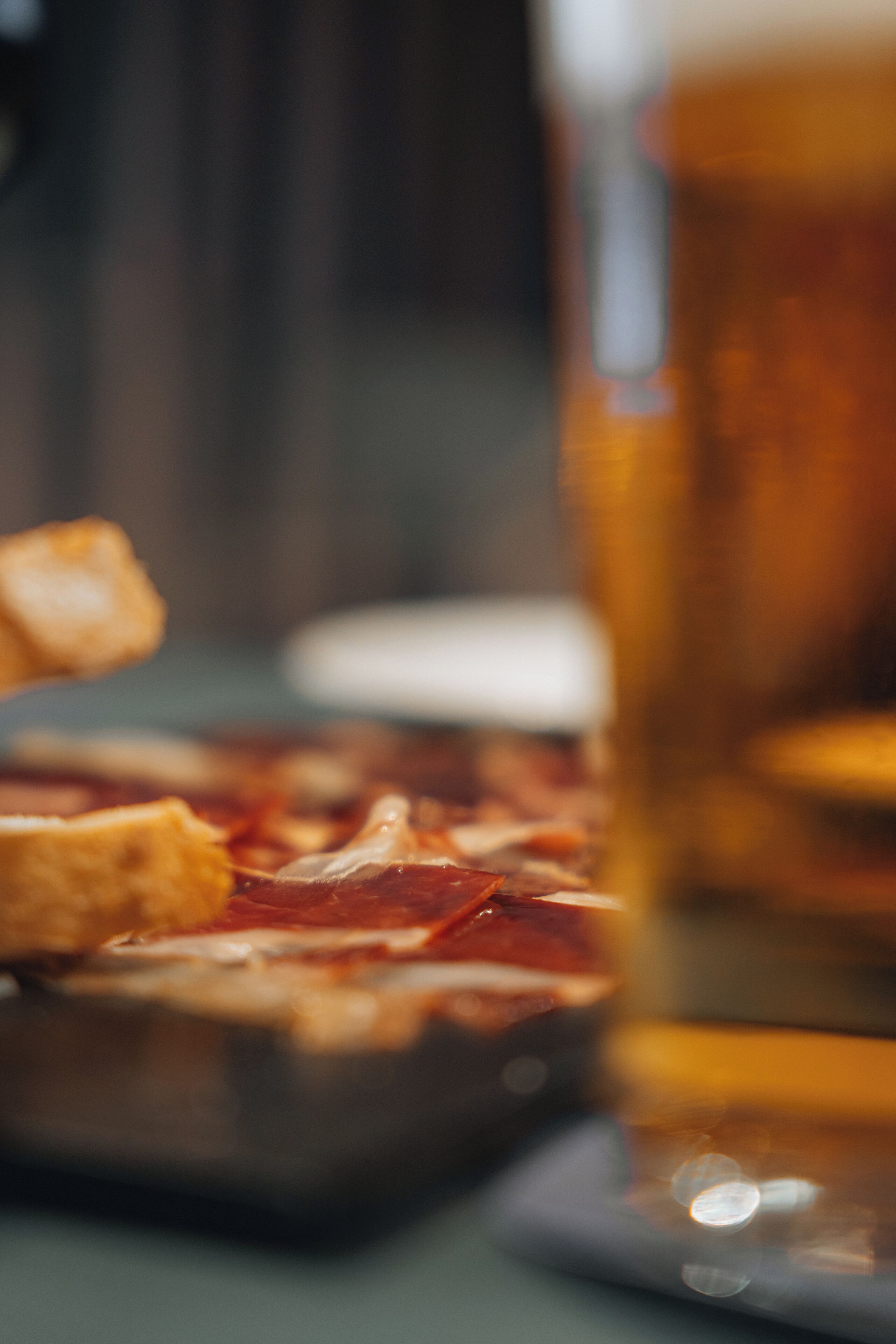 A close-up of a pizza with a glass of beer in the background.