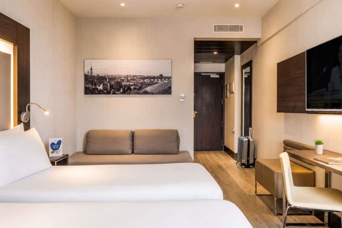 Ein Hotelzimmer mit Bett, Sofa, Schreibtisch und Fernseher.