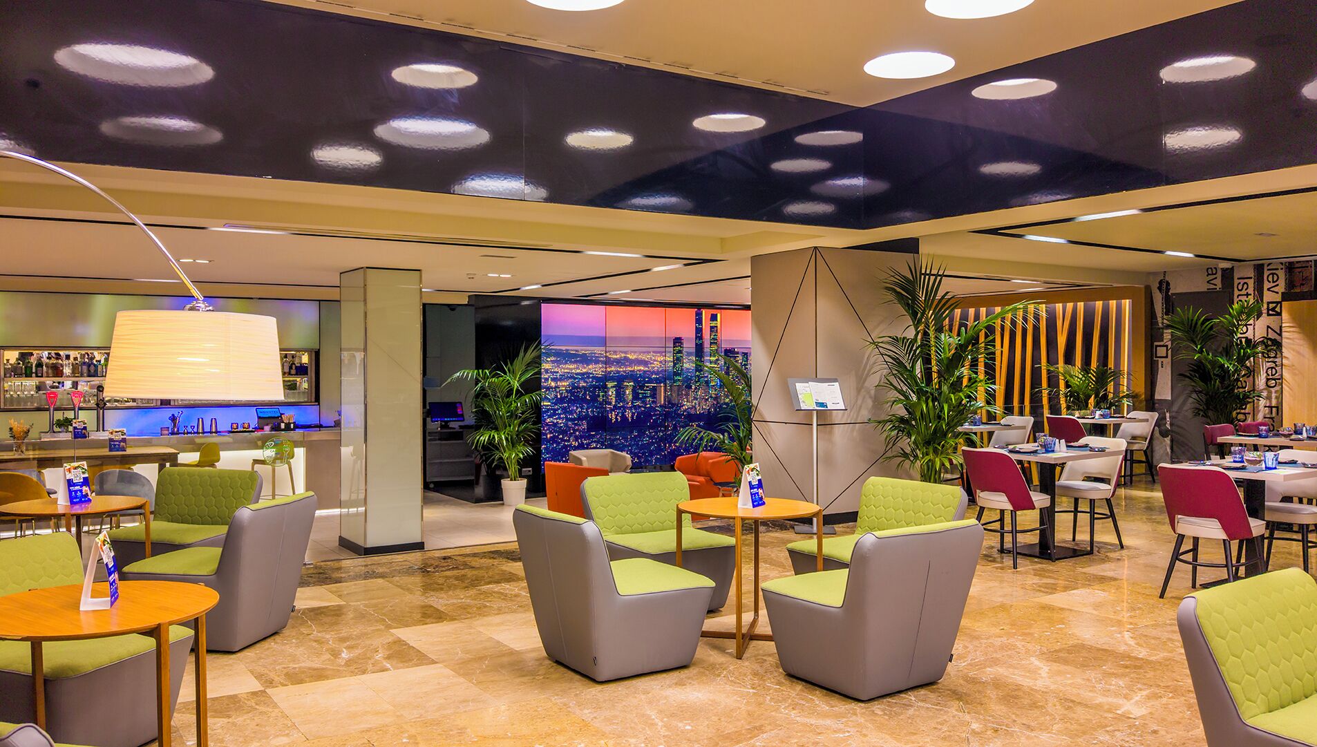 Un moderno vestíbulo de hotel con zonas de estar, un bar y un amplio ventanal con vistas a la ciudad.