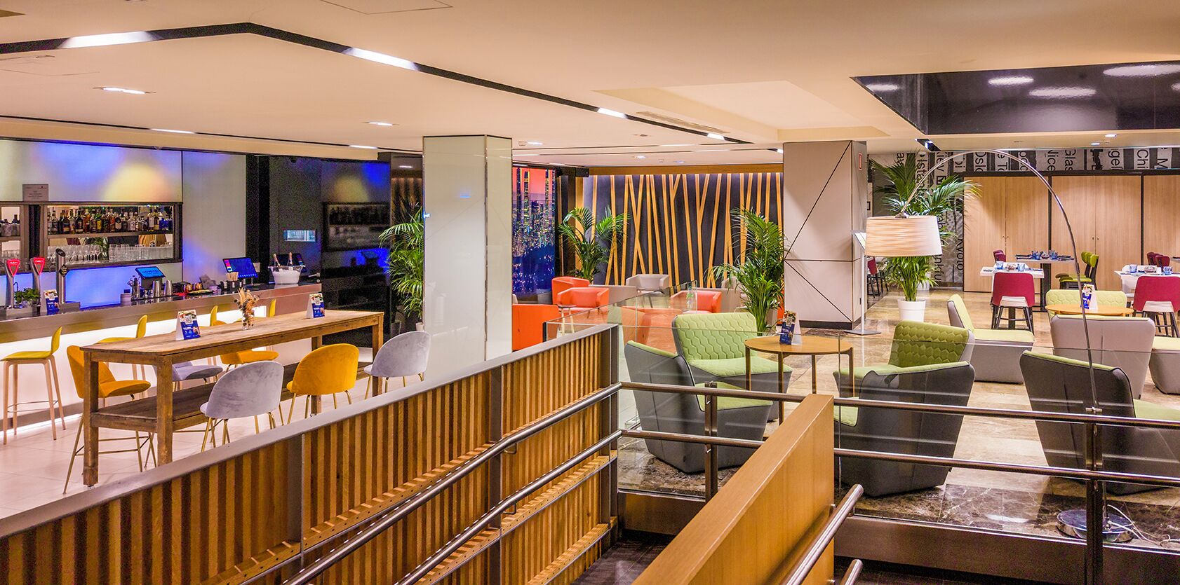 A modern hotel lobby with a bar area, seating arrangements, and a staircase.