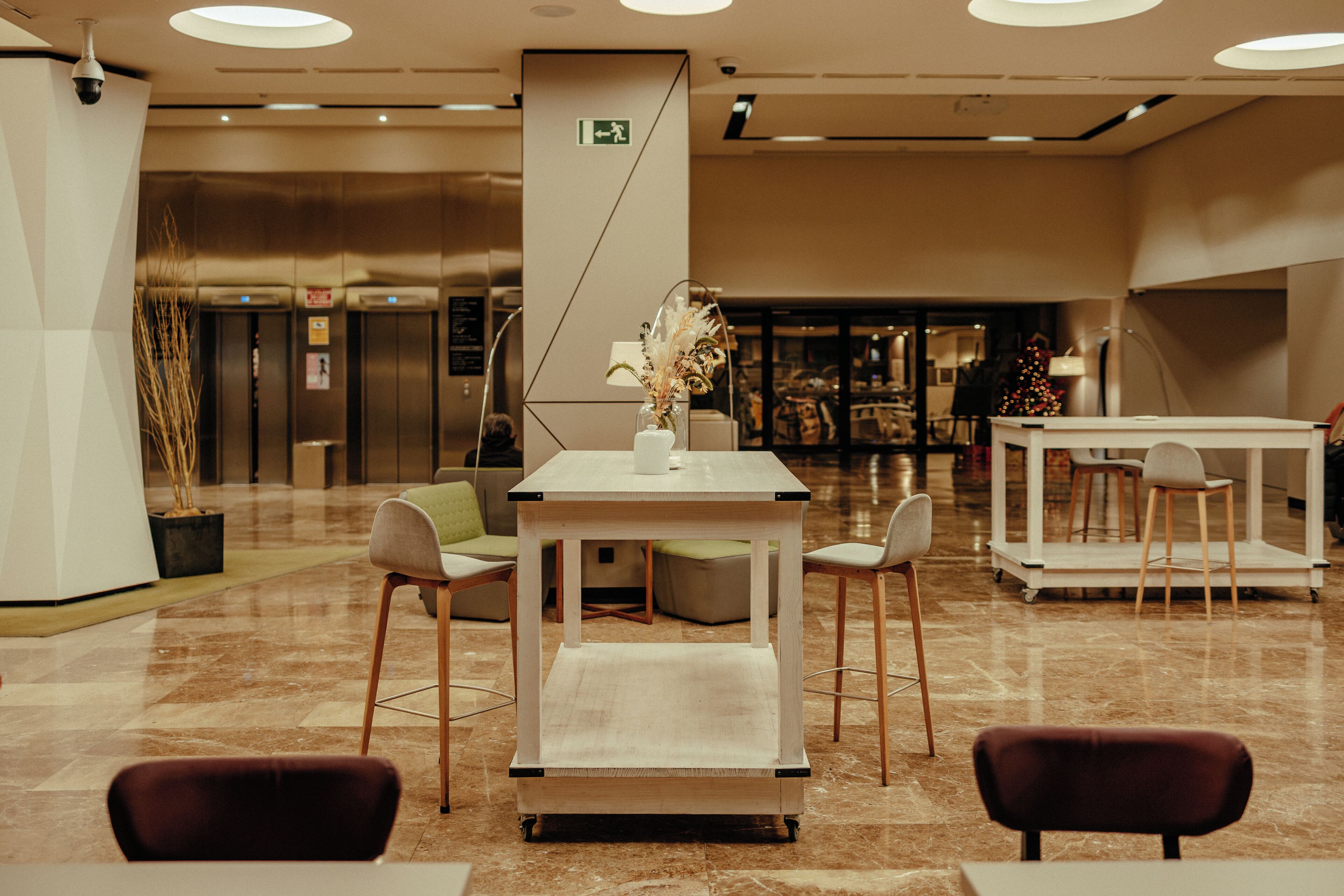 A lobby with a central table, seating, and a Christmas tree.