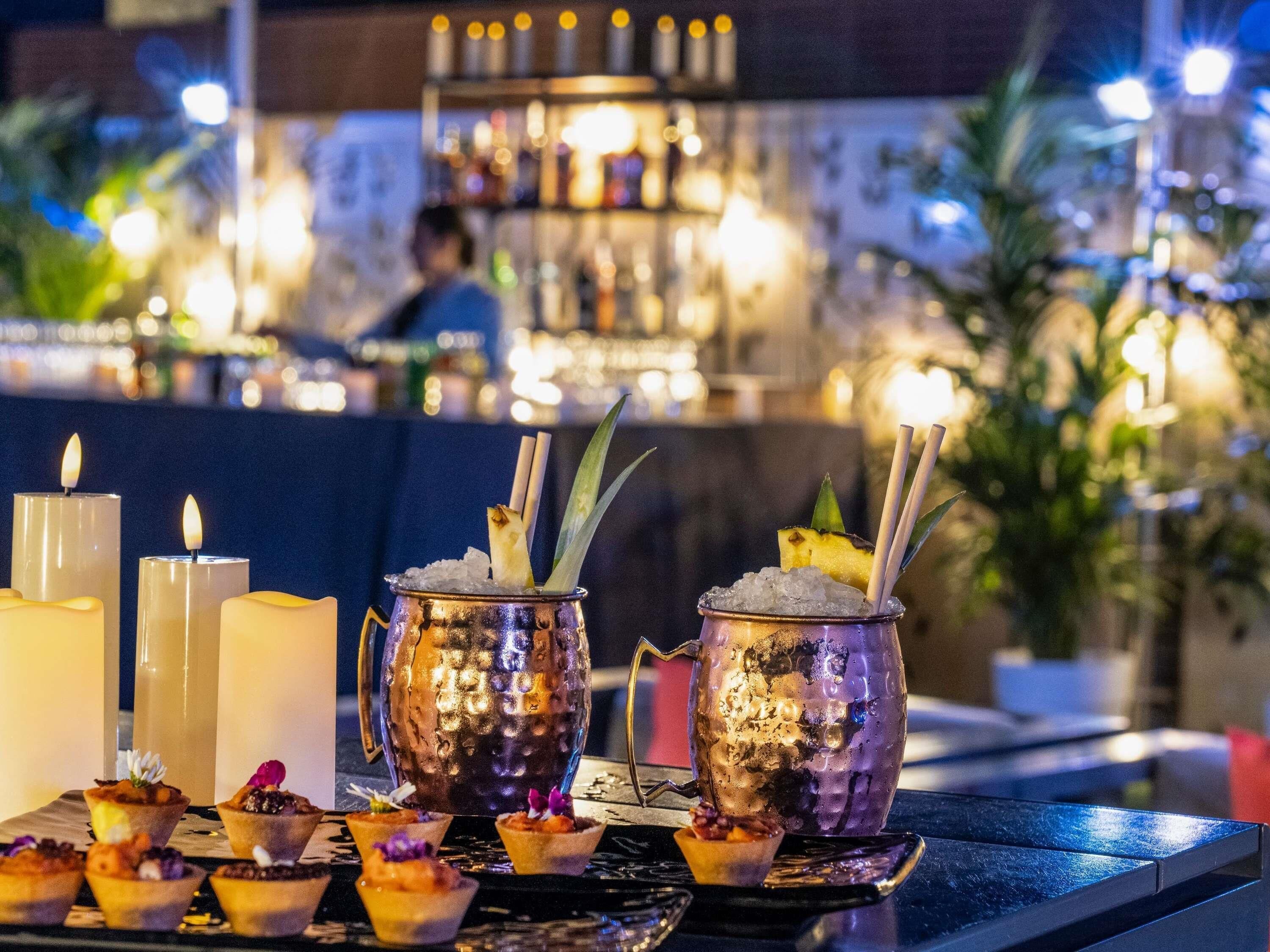 Zona de bar con bebidas, velas y una persona al fondo.
