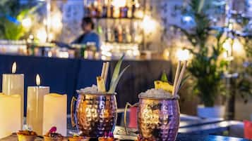 Zona de bar con bebidas, velas y una persona al fondo.