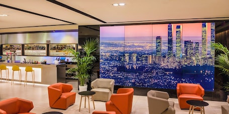 A modern bar area with a city view, orange seating, and a bar counter.