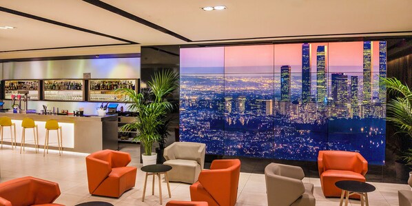 A modern bar area with a city view, orange seating, and a bar counter.