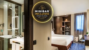Une chambre d’hôtel moderne équipée d’un grand lit, d’un bureau, d’une chaise, d’une petite table, d’une bibliothèque et d’une salle de bain avec un miroir et un lavabo.