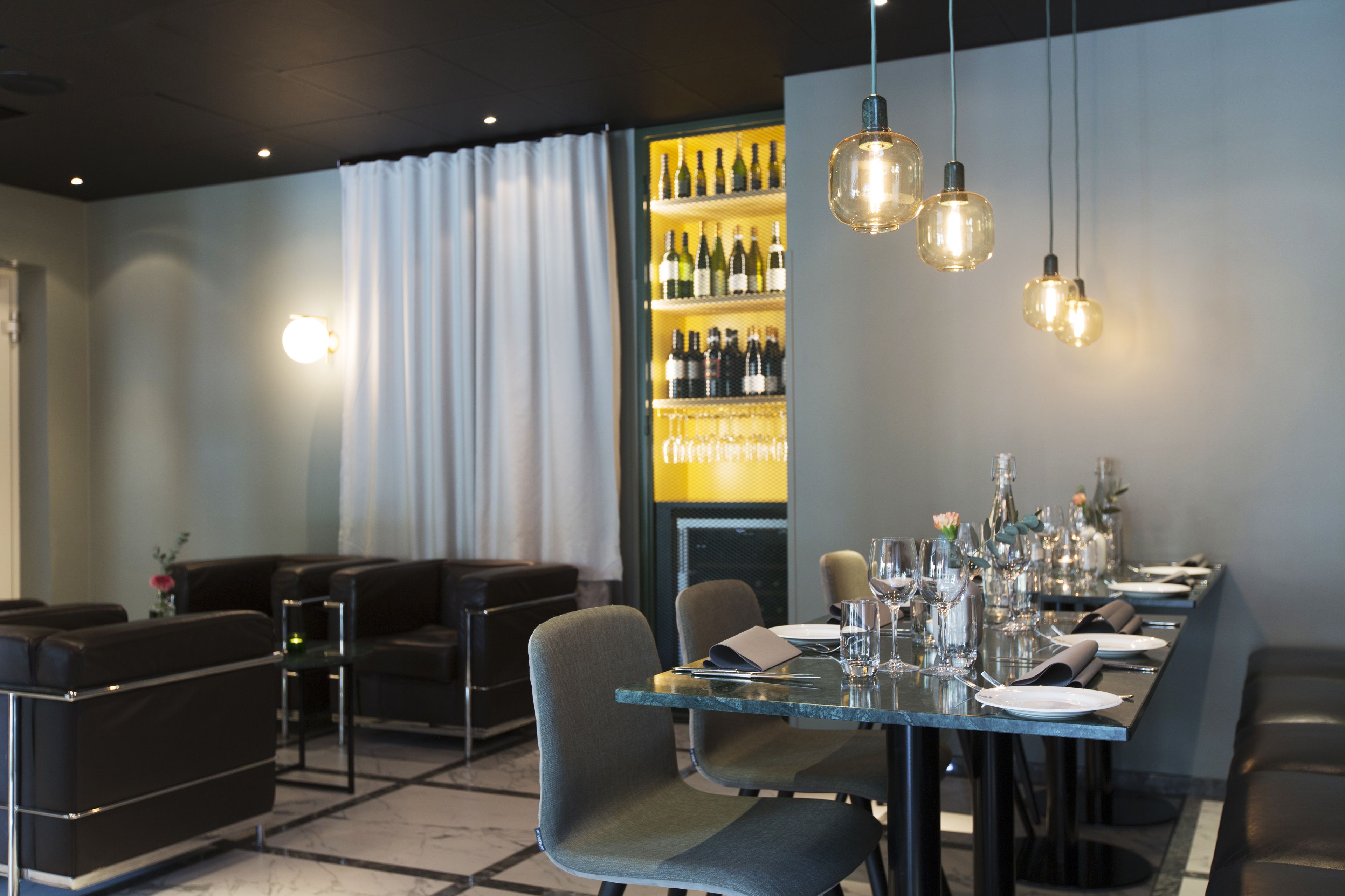 A modern dining area with a long table set for a meal, surrounded by comfortable seating.