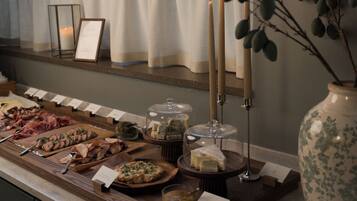 A buffet with various food items, candles, and a vase with branches.