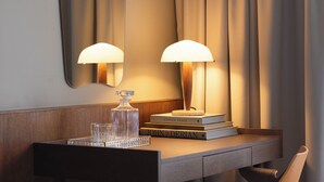 Una habitación de hotel con un escritorio de madera, dos lámparas, un espejo y una cama.