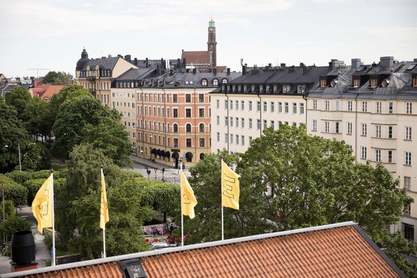 A view of a cityscape with historic buildings, a prominent clock tower, and flags on a rooftop. - Elite Hotel Arcadia (Stockholm)