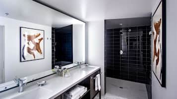 A modern bathroom with two sinks, a large mirror, and a shower area.