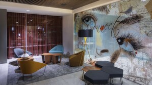 Un área de descanso moderna con un mural grande, asientos cómodos y una lámpara de pie.