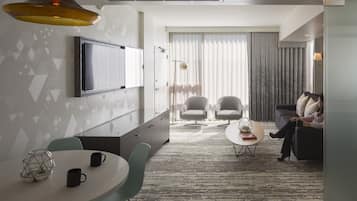 A modern living room with a TV, seating, and a dining area.