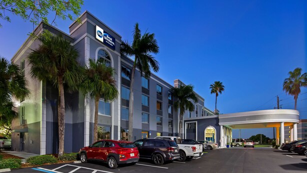 A hotel with a modern design, featuring a prominent 'Best Western' sign, multiple parking spaces, and palm trees.