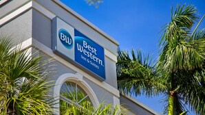 A Best Western Inn & Suites sign on a building with a clear blue sky and palm trees.