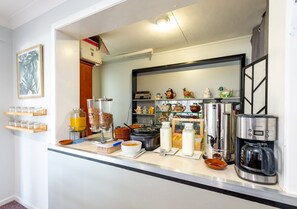 A breakfast bar with various food items and a coffee machine.