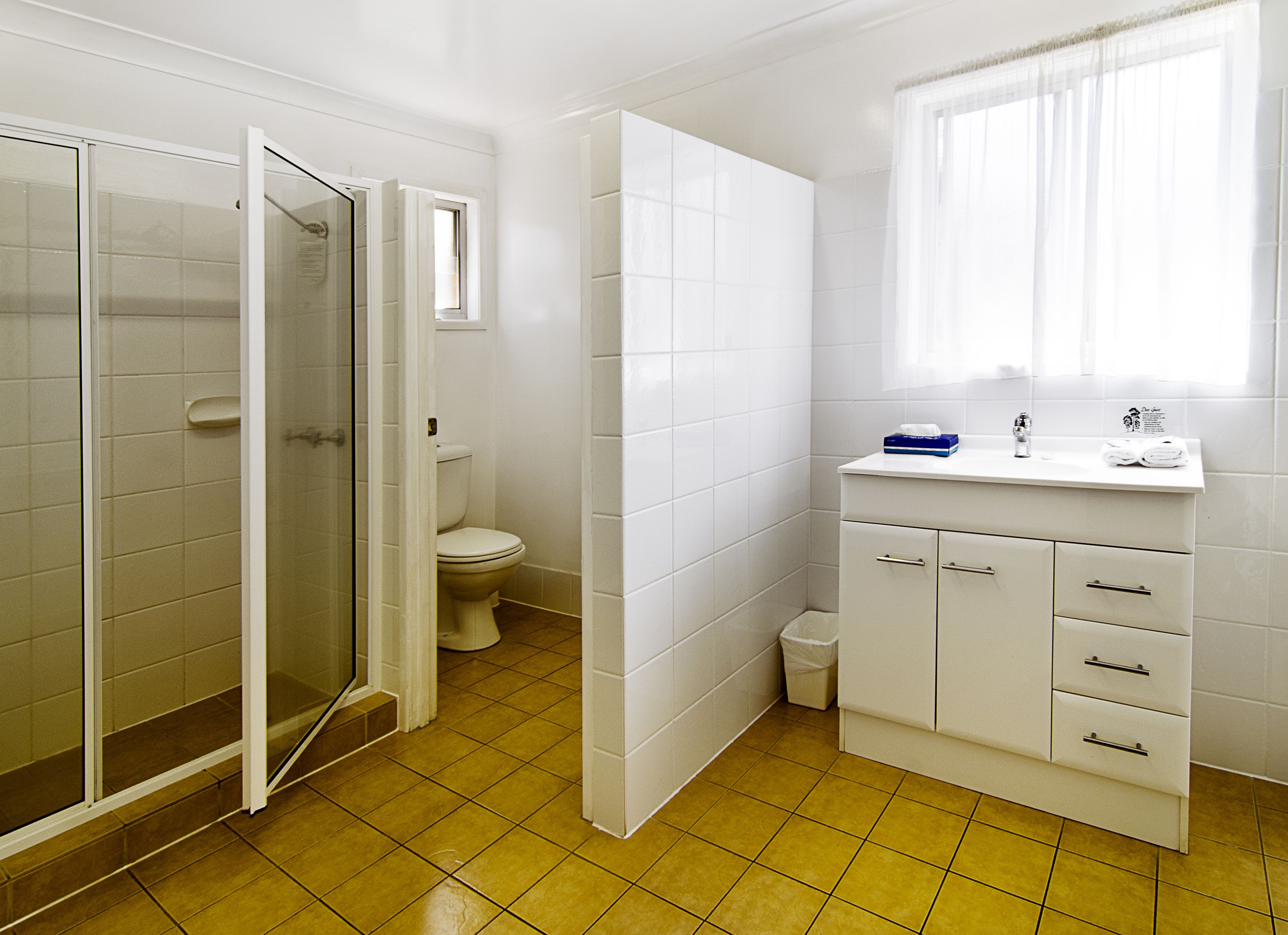 Une salle de bain équipée d’une douche, de toilettes, d’un lavabo et d’un meuble de rangement.