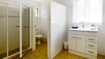 Une salle de bain équipée d’une douche, de toilettes, d’un lavabo et d’un meuble de rangement.