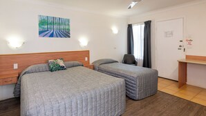 A room with two beds, a desk, a chair, and a painting on the wall. - Riviera on Ruthven Motel (South Toowoomba)