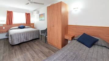 A room with two beds, a wardrobe, a desk, and a chair.