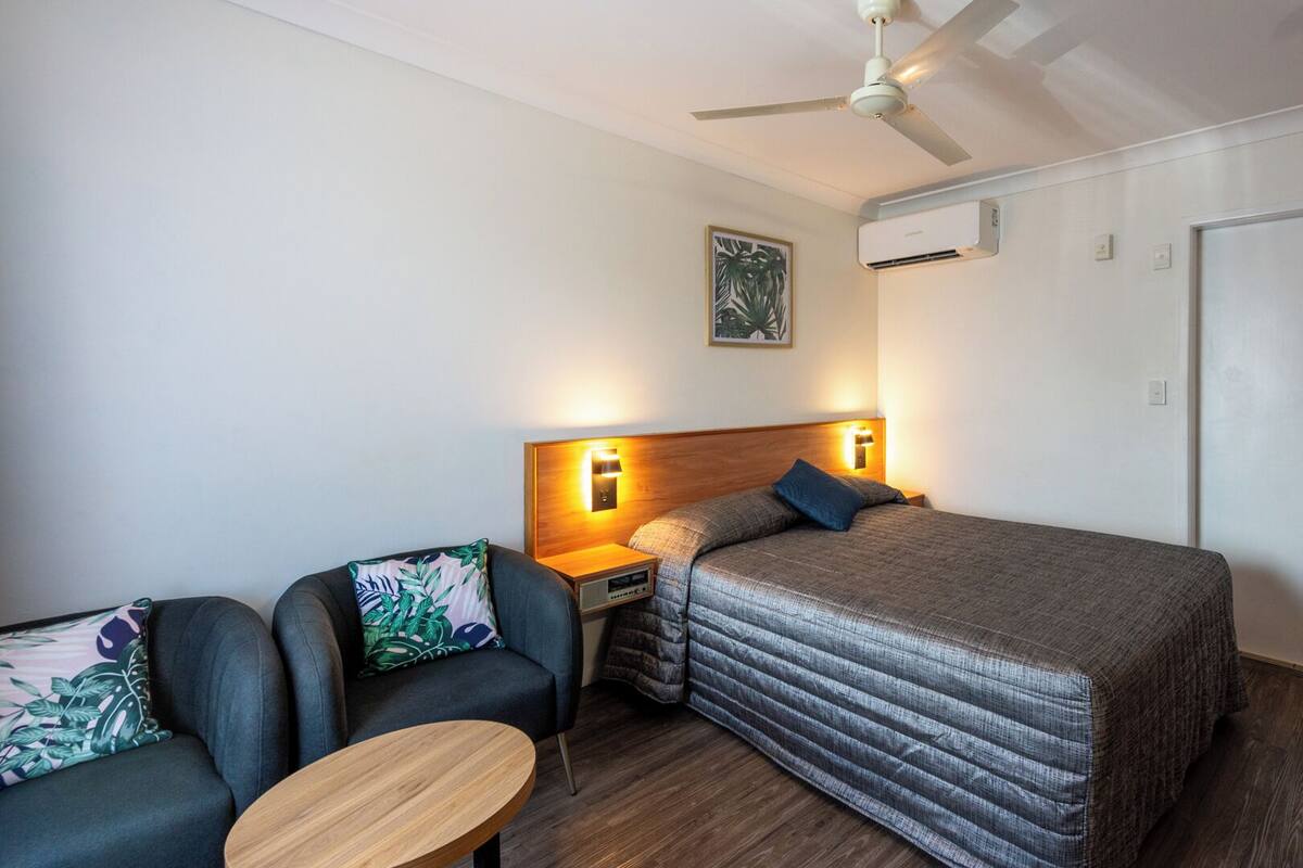 Una camera da letto con un letto, un comodino, una sedia, un tavolo, una ventola a soffitto e un condizionatore d'aria.