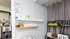 A kitchenette with a coffee maker, a plate of snacks, and a sign listing available jam flavors. - Riviera on Ruthven Motel (South Toowoomba)