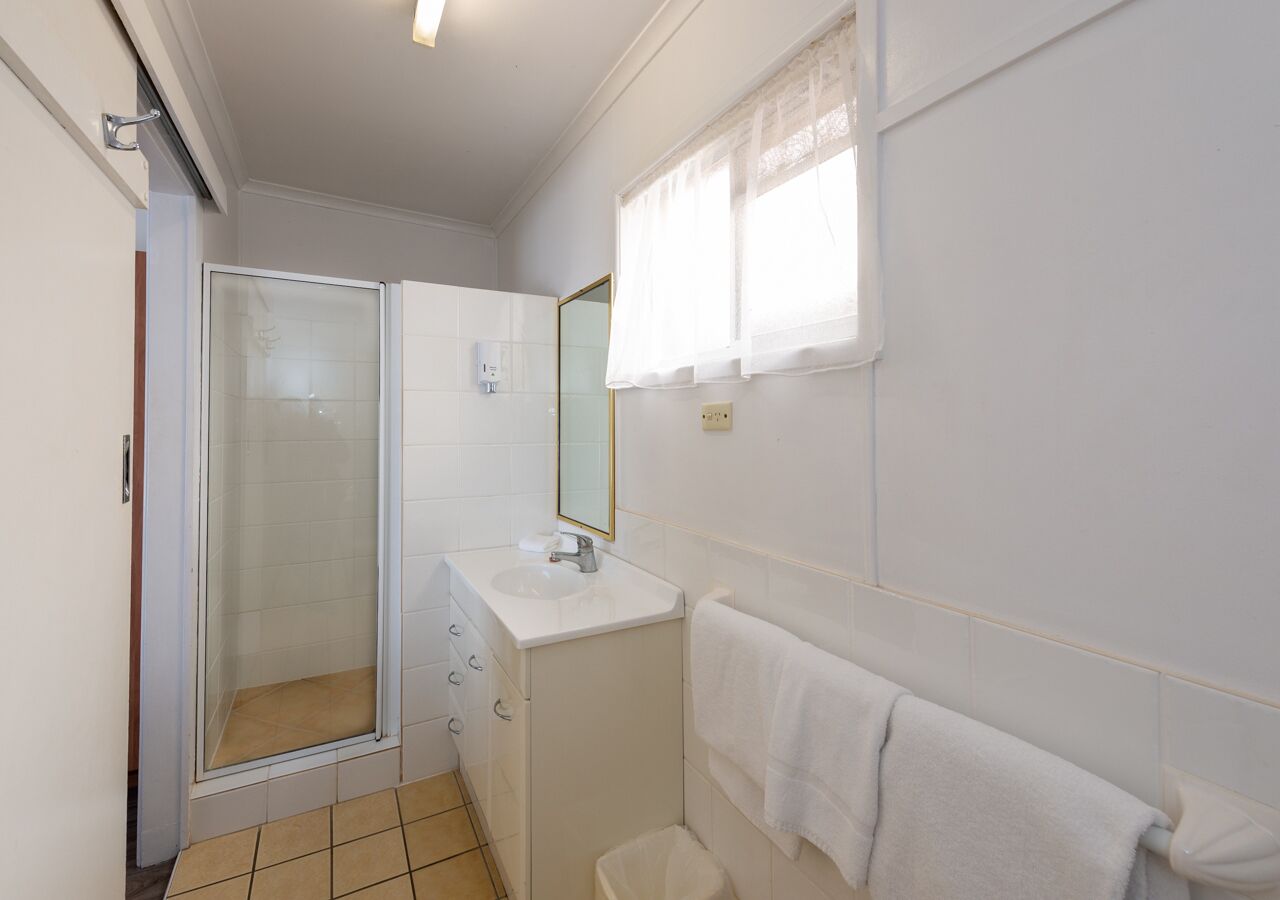 A small bathroom with a shower, sink, and a mirror.