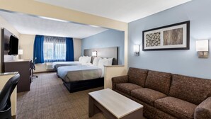 Een hotelkamer met twee bedden, een bank, een bureau en een televisie.