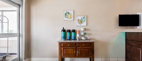 A kitchen with a wooden table, a TV, and artwork on the wall.