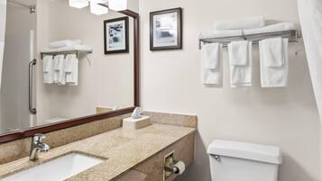 A bathroom with a sink, mirror, towel rack, toilet, and framed pictures on the wall.