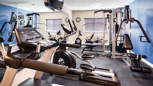 Een sportschool met diverse fitnessapparaten, waaronder loopbanden, hometrainers en krachttoestellen.