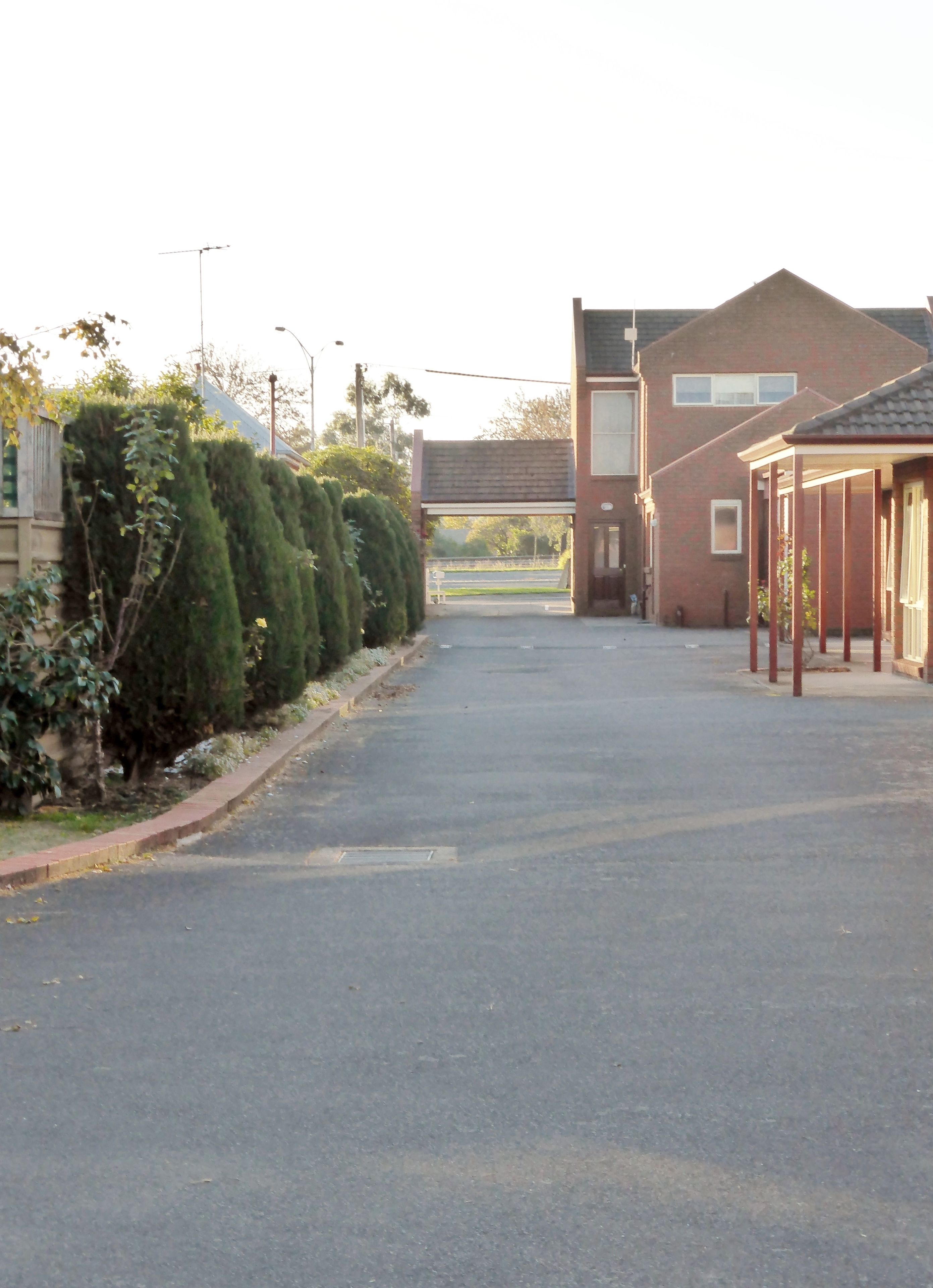 Une rue tranquille avec un immeuble doté d’un porche abrité et d’un garage.