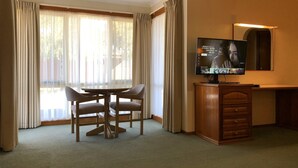 Une chambre d’hôtel équipée d’un coin repas, d’une télévision et d’un bureau.