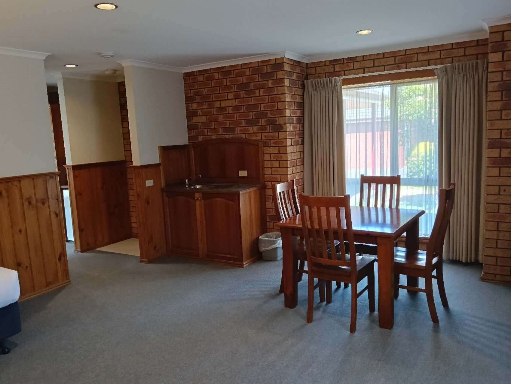 A dining area with a brick wall, wooden furniture, and a view through a window.
