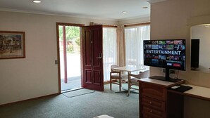 Une pièce comprenant un bureau, une chaise, un téléviseur et une porte donnant sur l’extérieur.