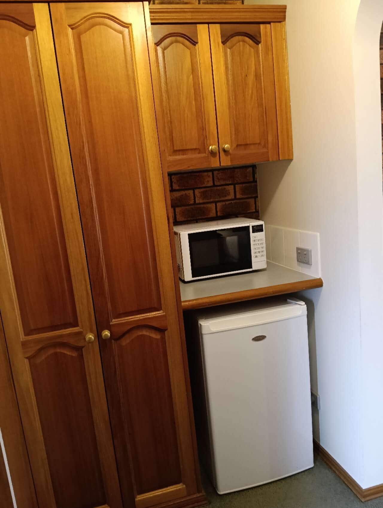 Una cocina con armarios de madera, microondas y refrigerador.