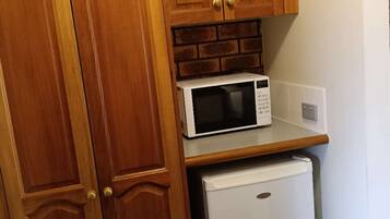 A kitchen with wooden cabinets, a microwave, and a refrigerator.