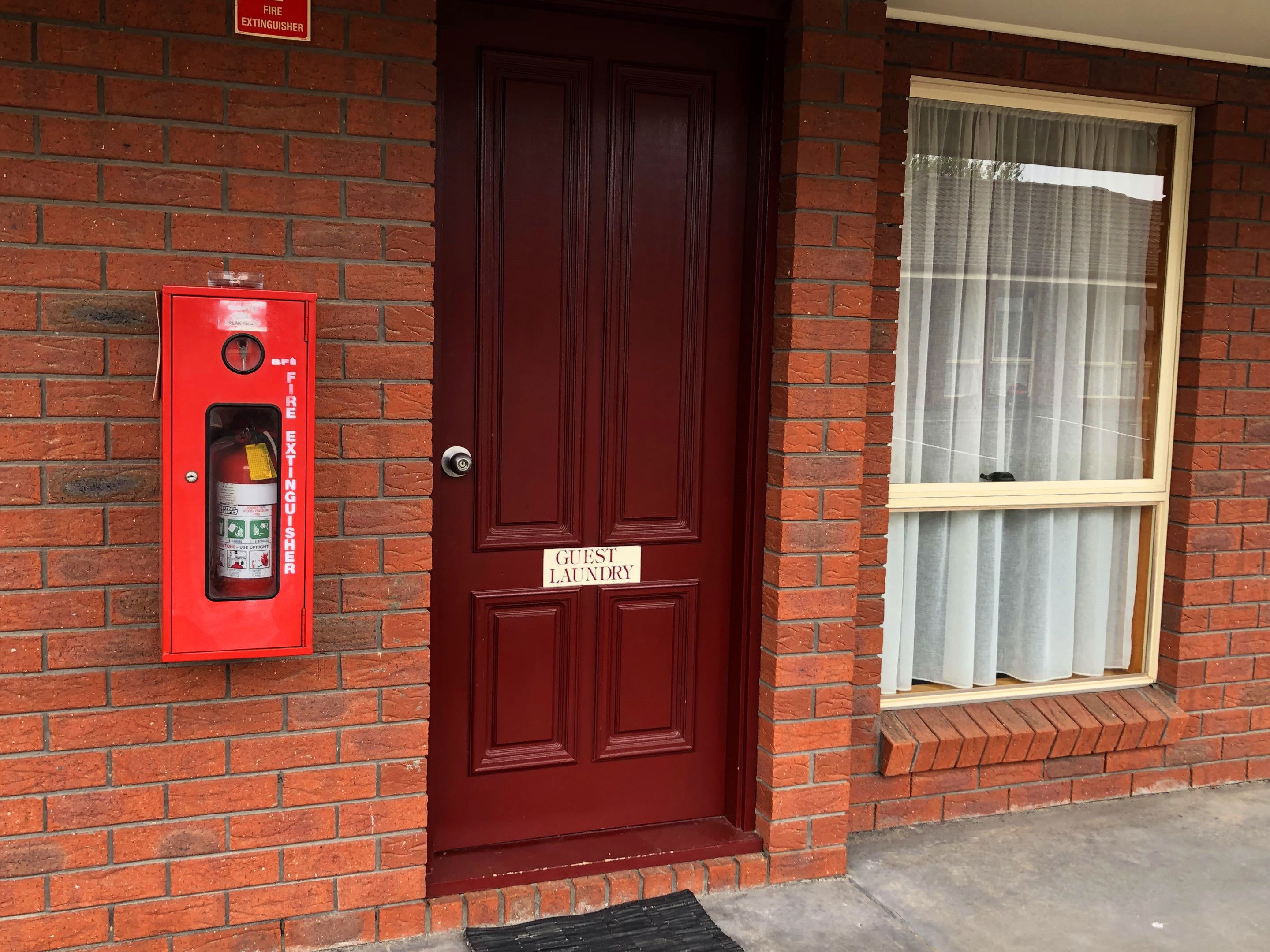 A red door with a fire extinguisher mounted on the wall to the left.