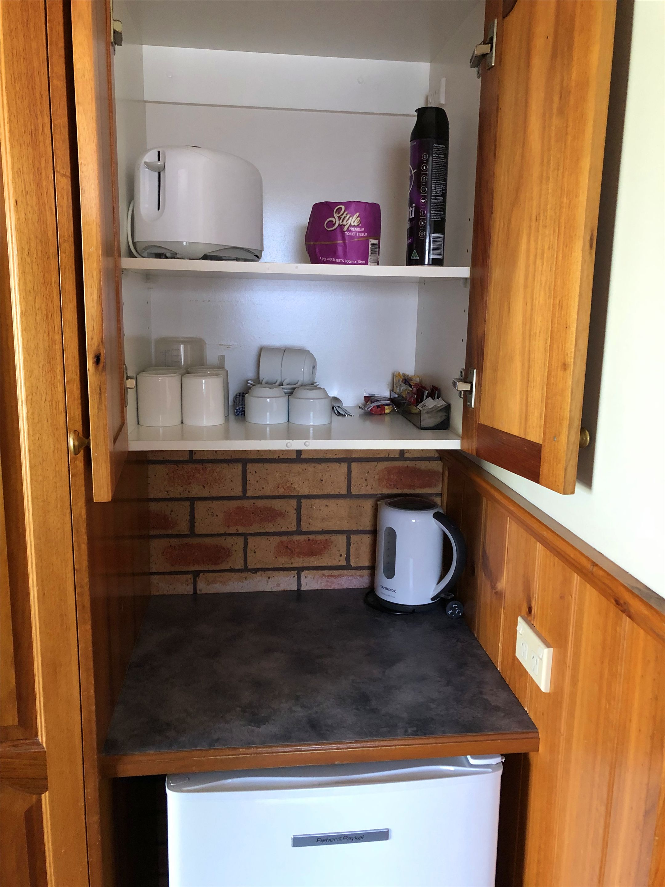 Een kleine keuken met een koelkast, een koffiezetapparaat en een waterkoker.
