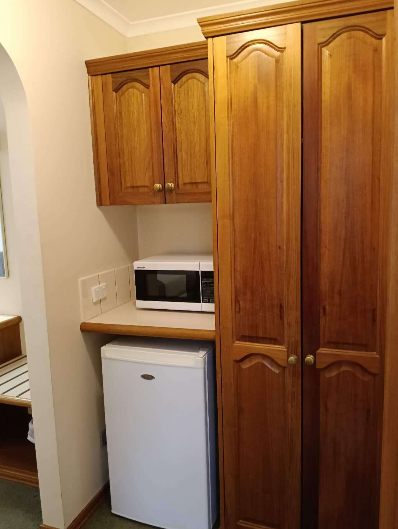 A kitchen with wooden cabinets, a white refrigerator, and a microwave.