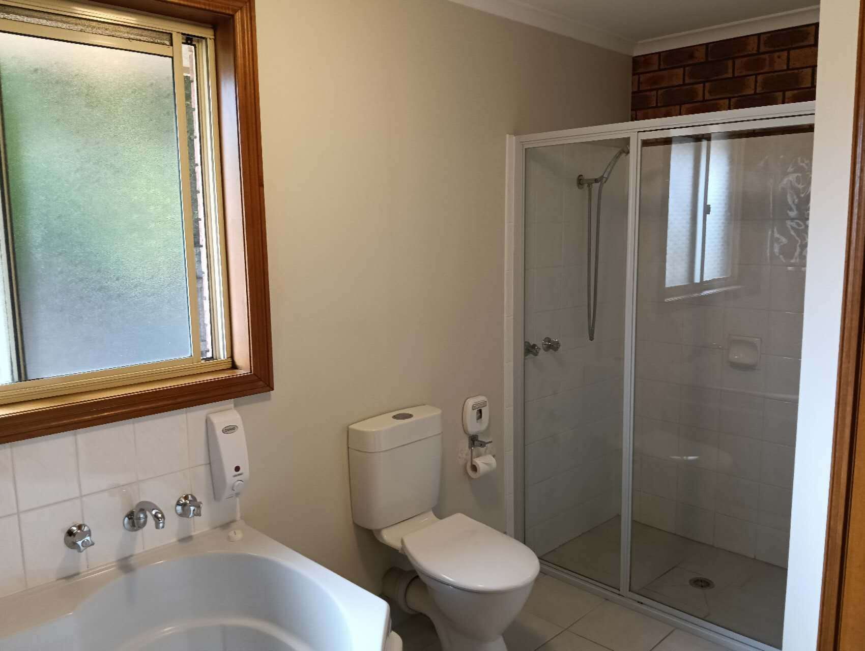 A bathroom with a bathtub, toilet, and glass-enclosed shower.