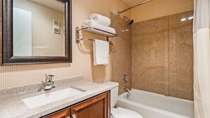A bathroom with a sink, mirror, towel rack, shower, and toilet.