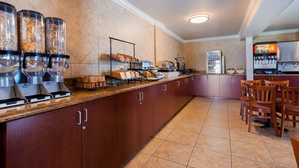A kitchen area with a coffee station, a refrigerator, and a seating area with chairs.