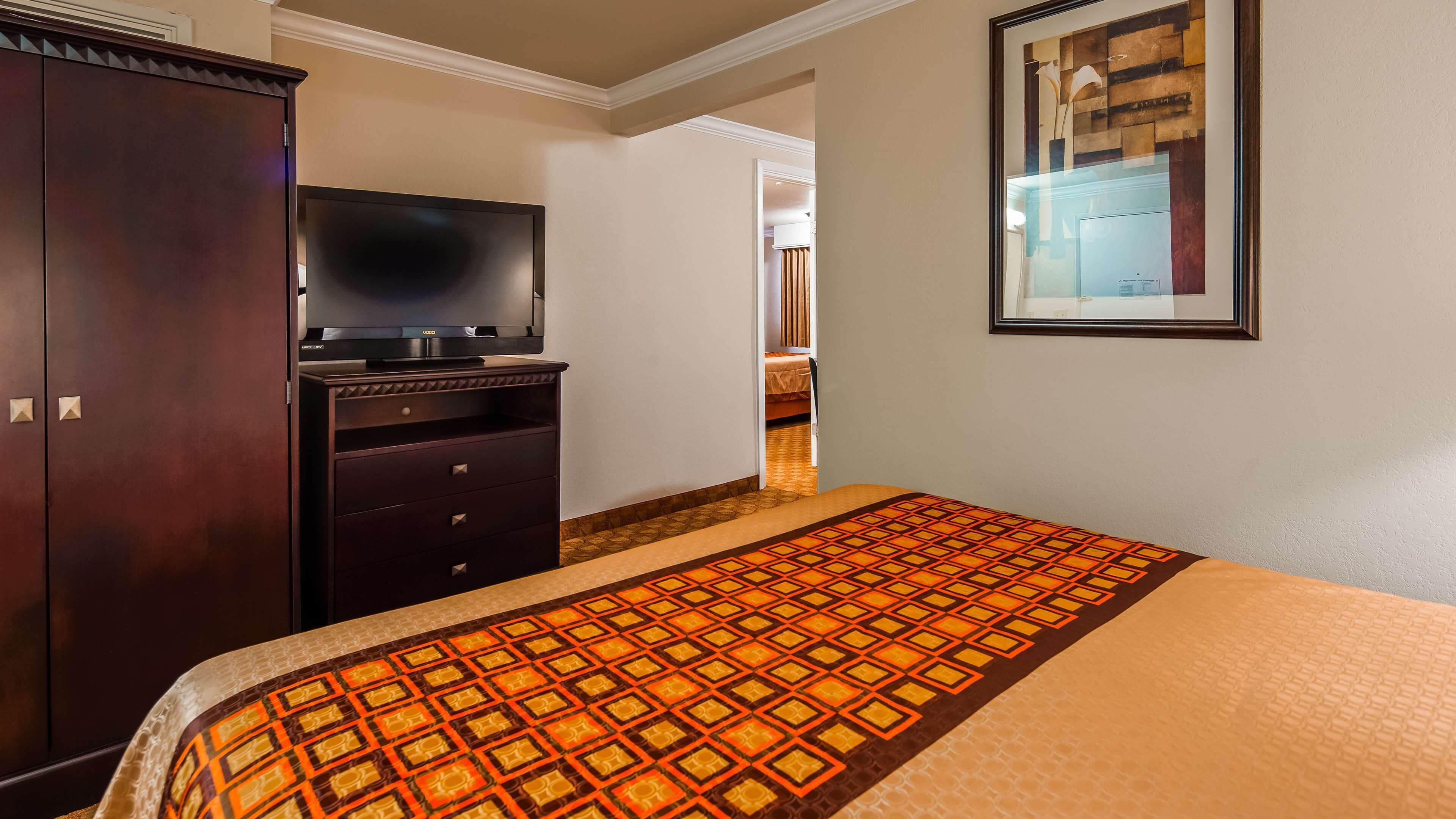 Une chambre d’hôtel comprenant un lit, une télévision, une armoire et une porte donnant sur une autre pièce.