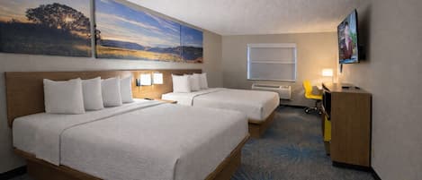 A hotel room with two beds, a desk, a chair, a TV, and artwork on the walls.