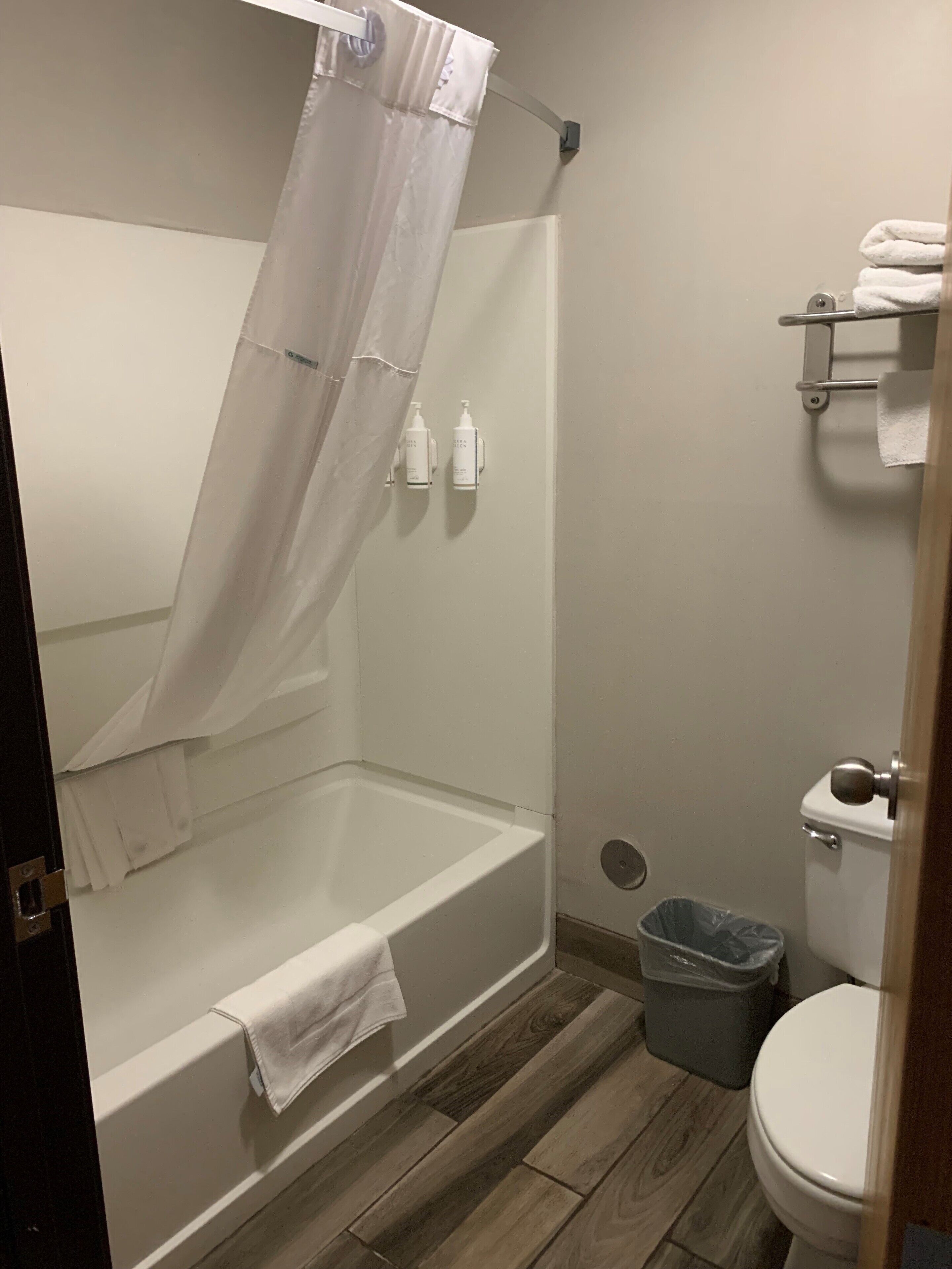 Une salle de bain avec une baignoire, des toilettes et une poubelle.