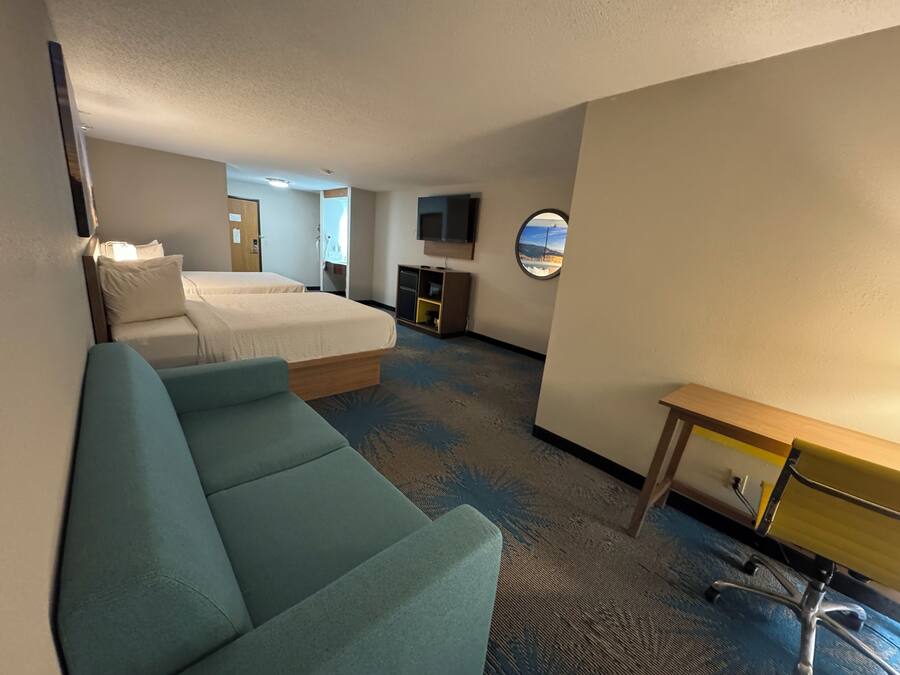 A hotel room with a bed, a desk, a chair, a TV, and a window with a view.